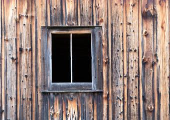 Close up of Distressed Barn Wall with Window has Light and Dark Boards with Discoloration and Nails.