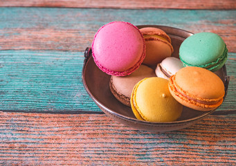 French macarons  in a metal cup on a wooden background.