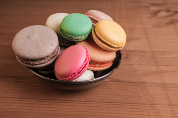 French colorful and tasty macarons in a bowl on a wooden table