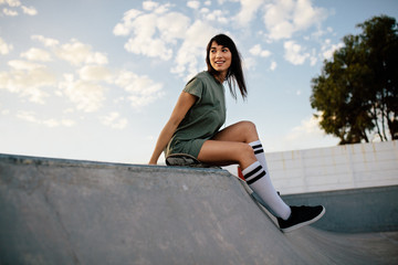Female skateboarder sitting on a ramp in skate park © Jacob Lund