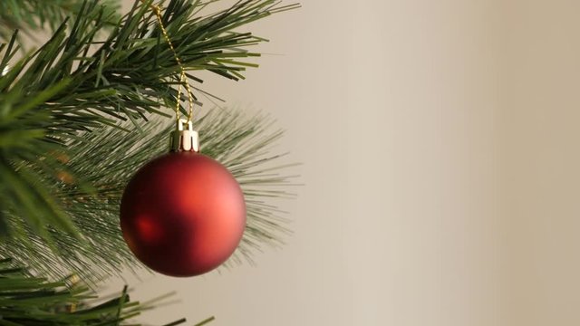 Matte color decorative bauble on the artificial tree branch footage - Red Christmas ornament close-up