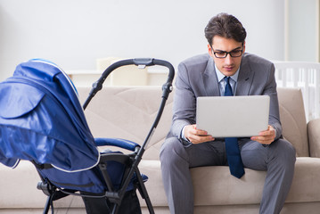 Businessman looking after newborn baby at home and teleworking