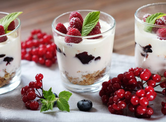 Healthy breakfast - yogurt with fresh berries and muesli served in glass jar, on wooden background