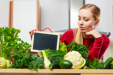 Woman having green vegetables holding board