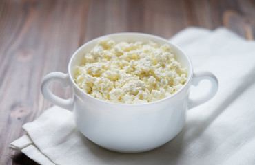Fresh cottage cheese in a  bowl on a wooden table.