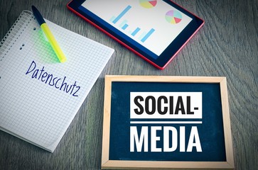 Plate with the inscription Social Media and in german Datenschutz in english Privacy with a tablet and blockto to symbolize the data scandal