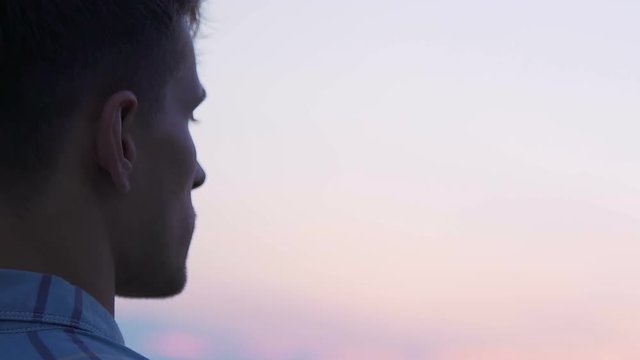 Young man looking at sky over city, enjoying nature view, thinking over decision