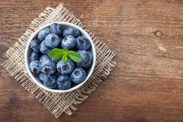 Blueberry on wooden table background. Ripe and juicy fresh picked blueberries closeup. Berries closeup top view with copy space