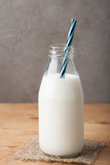 Bottle of milk on a wooden table over dark background with copy space
