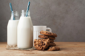 Two bottles of milk and chocolate chip cookies on dark background with copy space