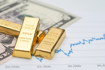Gold bullion ingot stack on america US dollar banknote money and rising price graph as crisis safe...
