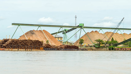 wood chip stockpile factory on Mahakam riverbank. industrial background