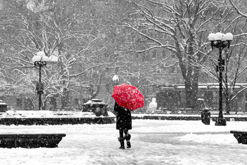 Woman with red umbrella in black and white New York City snow