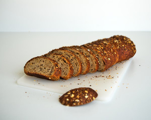 whole grain bread partially sliced loaf isolated on white background