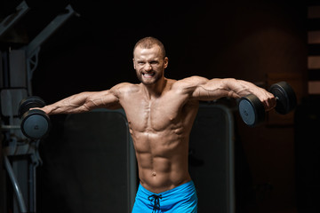 Fototapeta na wymiar Handsome powerful athletic man having weight training in gym