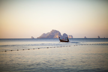 Naklejka na ściany i meble Lonely boat silhouette in the sea, on the sunrise, Krabi, Thailand