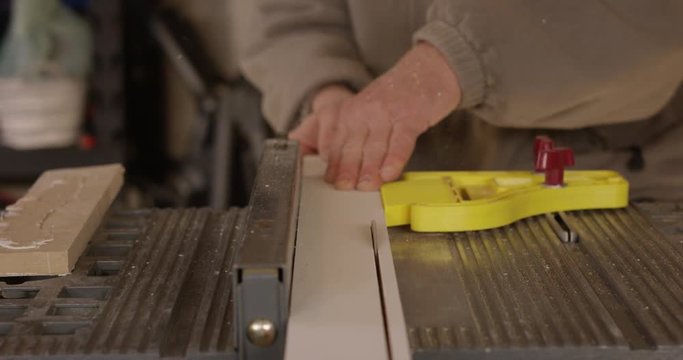 Man performs rip cut on table saw in workshop - slow motion head on shot