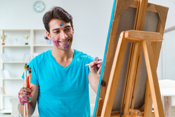 Young funny artist working on new painting in his studio