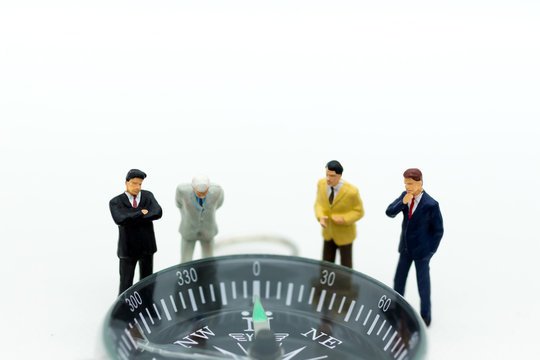 Miniature people :Businessman standing with compass. Image use for direction of the economy, investment for long-term profit.