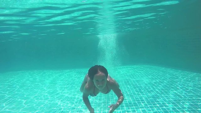 Young pretty woman jumps in swimming pool and swims underwater. 1920x1080