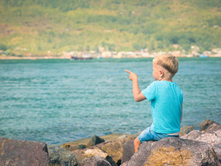 Cute caucasian boy pointing at seaside
