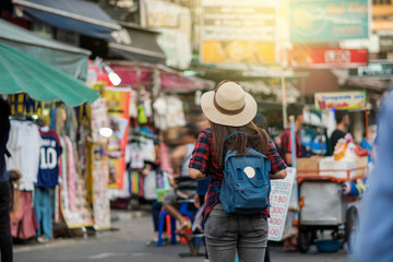 Back side of Young Asian traveling women walking and looking in Khaosan Road walking street in evening at Bangkok, Thailand, traveler and tourist concept - obrazy, fototapety, plakaty