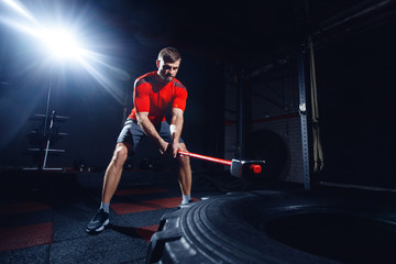Obraz na płótnie Canvas Sports training for endurance, man hits hammer with heavy hammer, sledge hammer. Concept workout