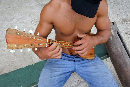 Above view of a Polynesian Cook Islander man plays music on Ukulele.Guitar in Rarotonga, Cook Islands