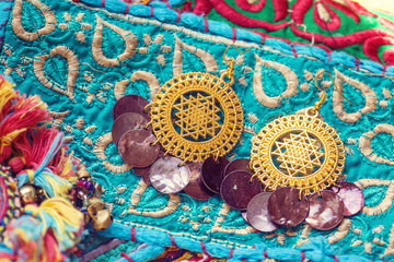 golden plated earrings on blue decorative textile