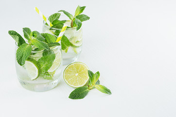 Cocktail mojito, straw and ingredients on soft white wood board, copy space, top view.