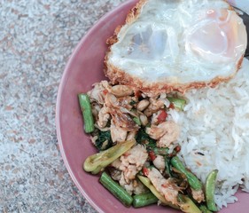 Stir fried spicy chicken with Thai basil and sweet pepper, eat with rice and fried egg. This is one of famous Thai food.