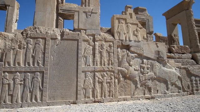 The facade wall Xerxes (Hadish) palace with carved sculptures of soldiers, courtiers, animals and ancient inscriptions, Persepolis, Iran.