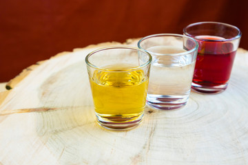 The wineglasses in the quantity of three pieces are put in a row on a wooden cut of the stump, the blurred background