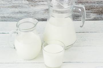 Milk in the glass jugs on the wooden background