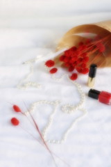 Obraz na płótnie Canvas Blure effect, soft focus. Dry red twigs with necklace and red nail polish on a white linen background. top view. Copy space
