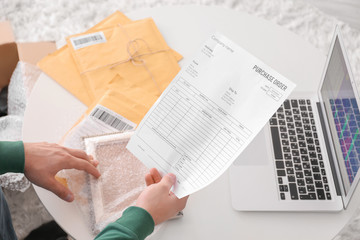 Naklejka premium Young man with purchase order sheet for parcel at home