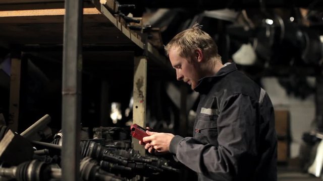 mechanic with an auto-scanner in a dark auto parts warehouse