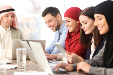 Office employees and their Muslim coworkers having business meeting in office