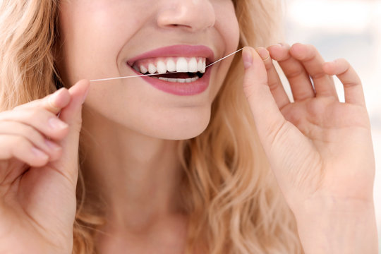 Young woman flossing her teeth, closeup