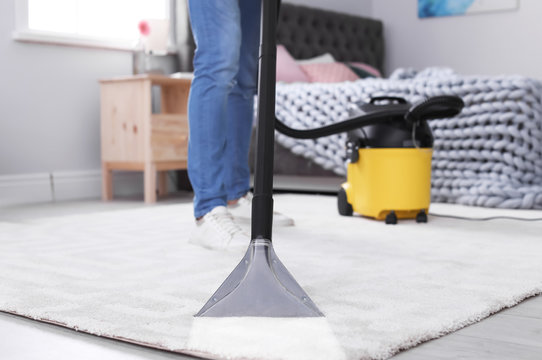 Mature man hoovering carpet with vacuum cleaner at home