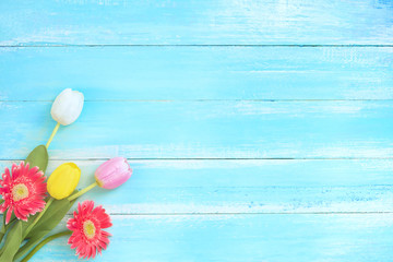 Colorful flowers bouquet on blue wooden background.  Concept flowers of spring, top view and border design