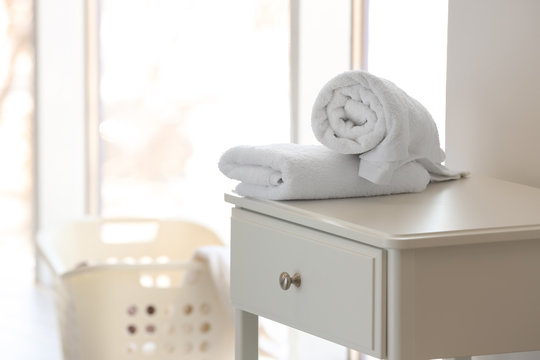 Clean towels on table and blurred laundry basket indoors