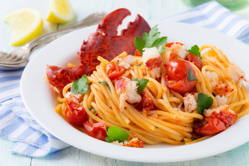 Spaghetti with lobster and cherry tomatoes served on white plate