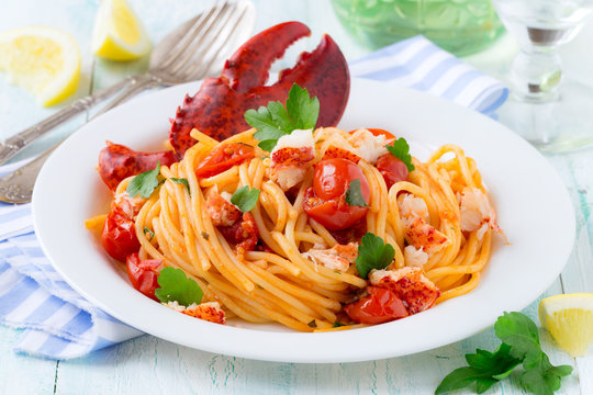 Spaghetti with lobster and cherry tomatoes served on white plate