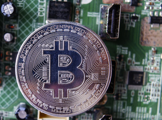 Silver souvenir coin Bitcoin on computer circuit board background.