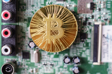 Gold souvenir coin Bitcoin on a computer circuit board background.