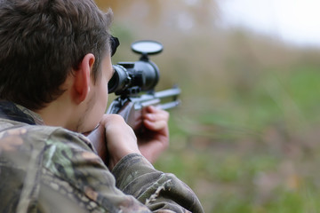Man in camouflage and with guns in a forest belt on a spring hun