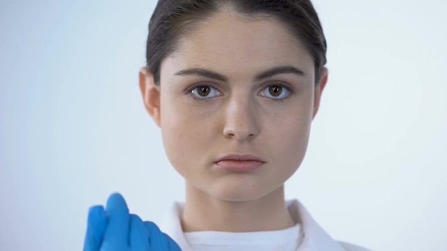 Female doctor wearing surgical mask, looking into camera as if examining patient