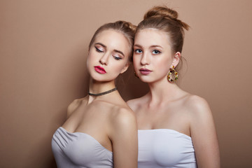 Two sexy young blonde hair girls hugging, earrings in ears jewelry on neck and, beautiful eyes. Summer skin care eye shadow, fashion natural skin care, face skin art, body beauty nature, spring makeup