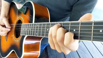 Obraz premium Acoustic guitar. A man plays an guitar with two hands close-up picture